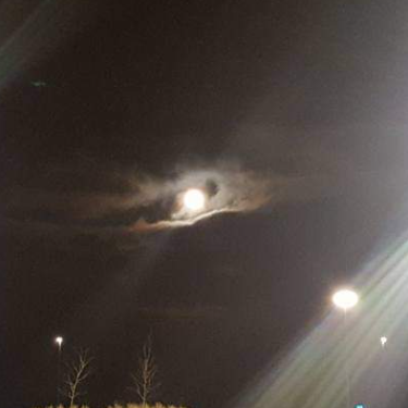 Image of moon in dark sky through clouds